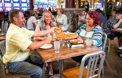man and two women sitting around a table eating pizza