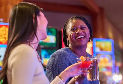 Two women laughing while playing slots