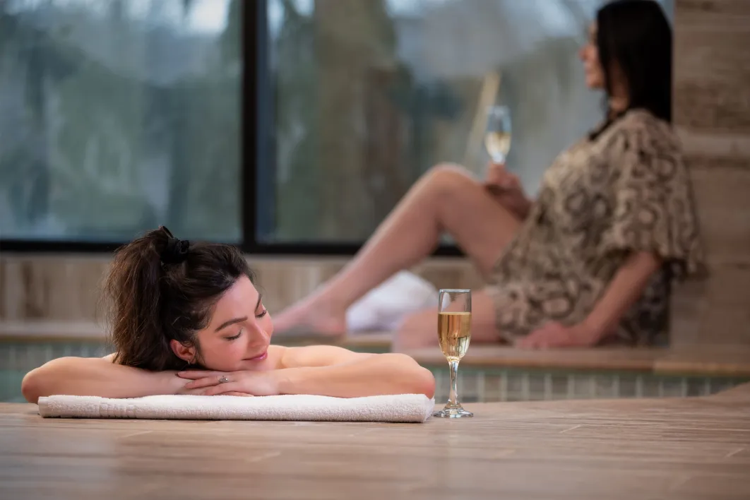 Woman at the edge of pool with her eyes closed next to wine glass