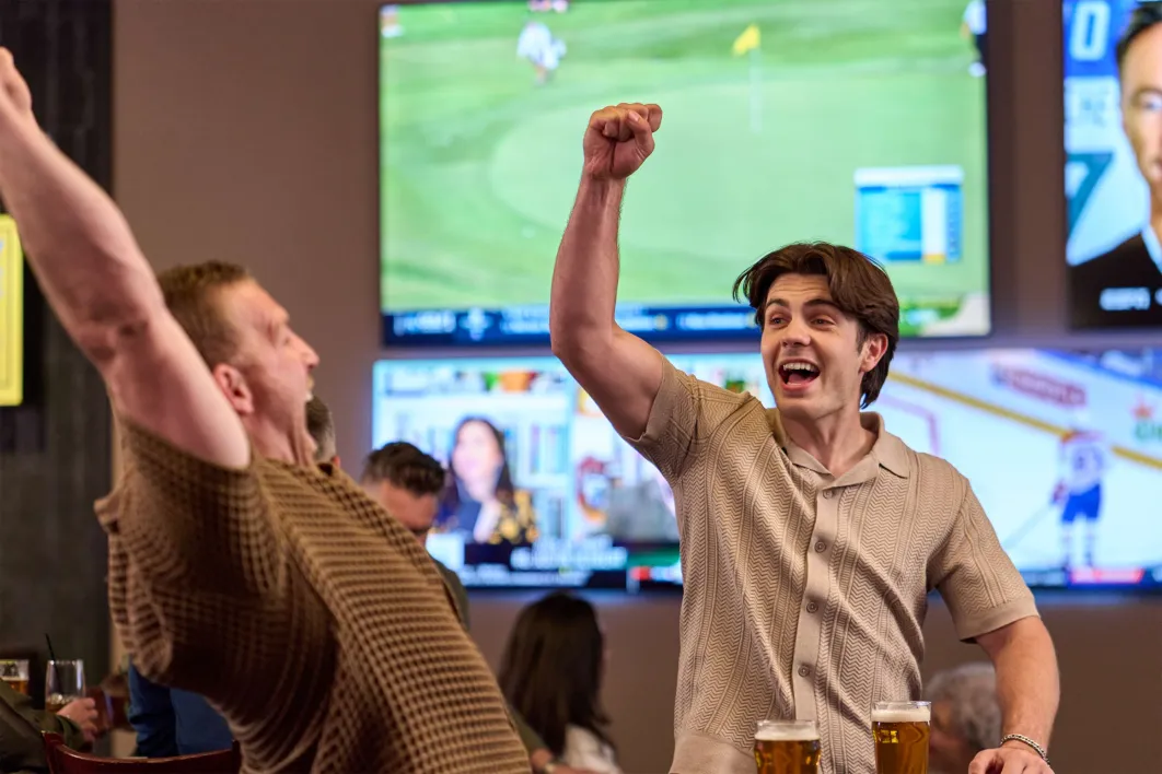 two men cheering with televisions in the background at Sportsbook at Little River Casino Resort in Manistee Michigan